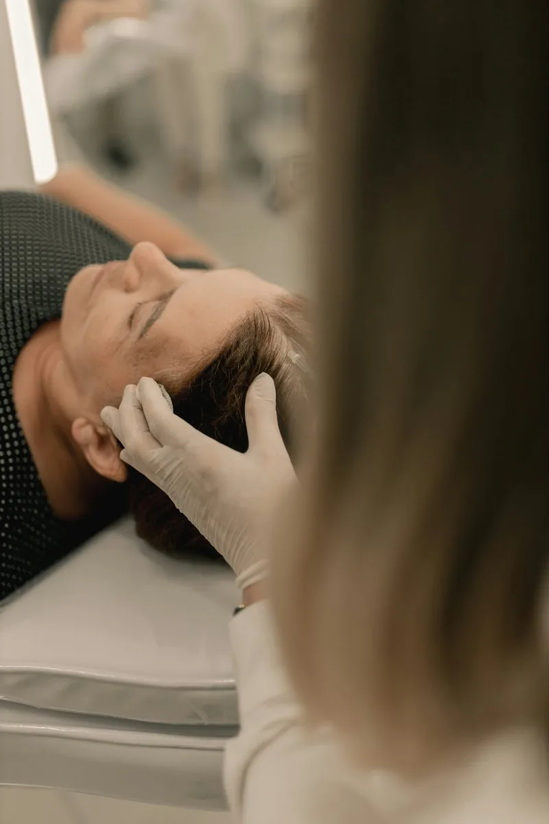 Dra. Karina Zold avaliando a pele do rosto de paciente em consulta dermatol&oacute;gica em Campinas
